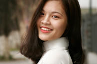 Portrait of a smiling young woman with natural light and soft background.